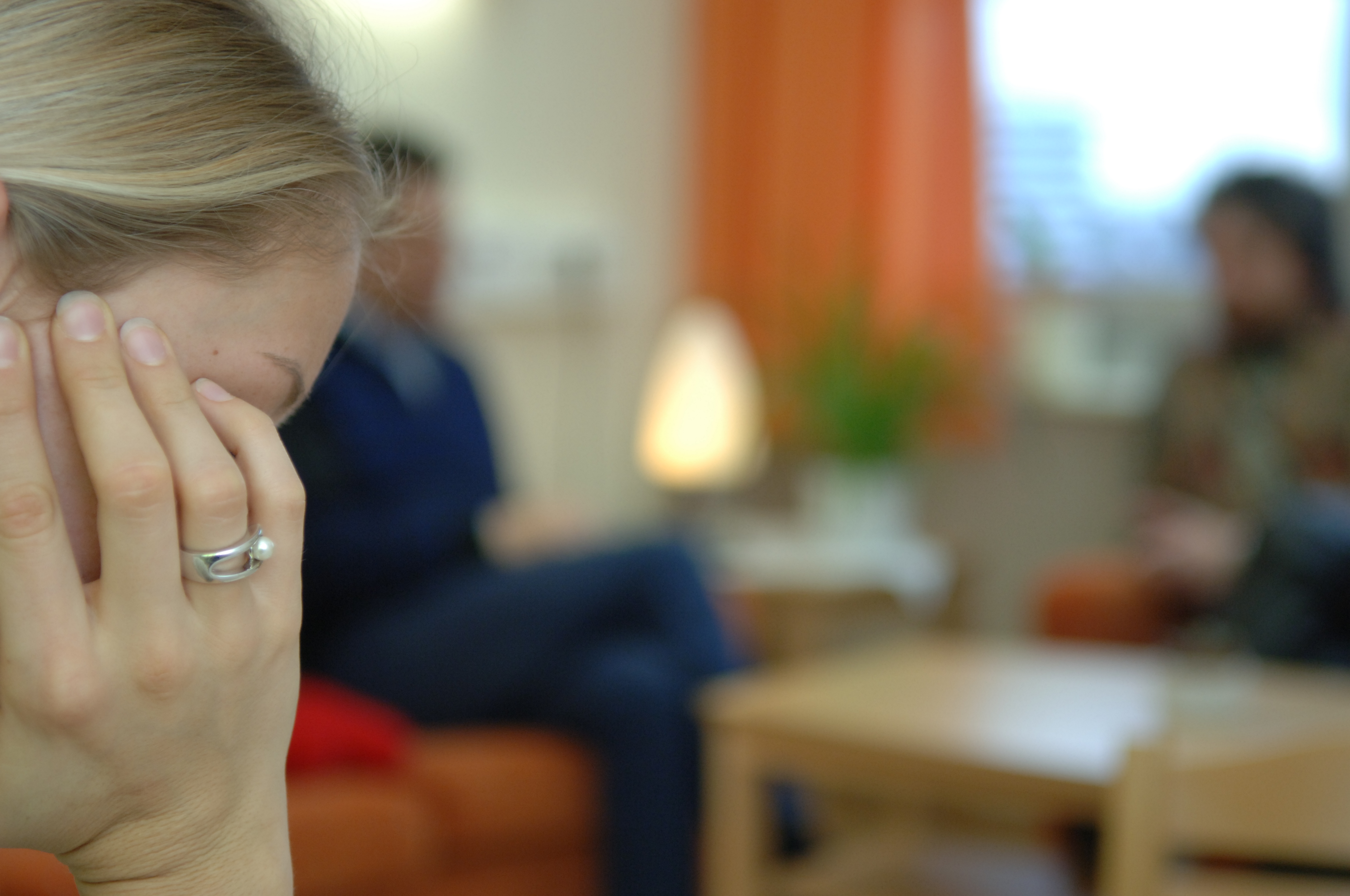 Frau im Vordergrund, lesend. Menschen sitzen im Hintergrund